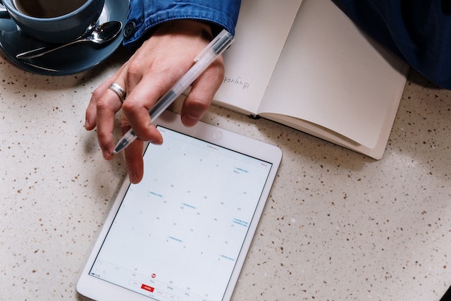 person using an ipad to schedule something in a calendar